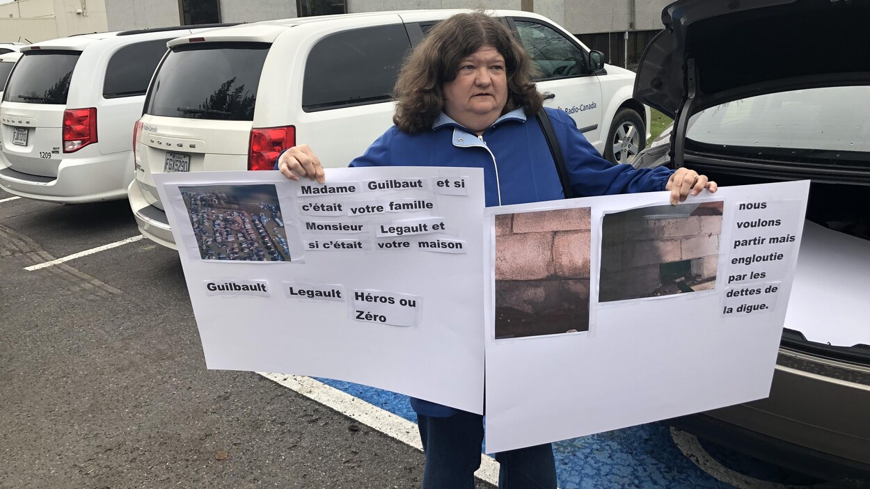La femme tient deux pancartes où on peut lire notamment : «Madame Guilbault et si c'était votre famille. Monsieur Legault et si c'était votre maison».
