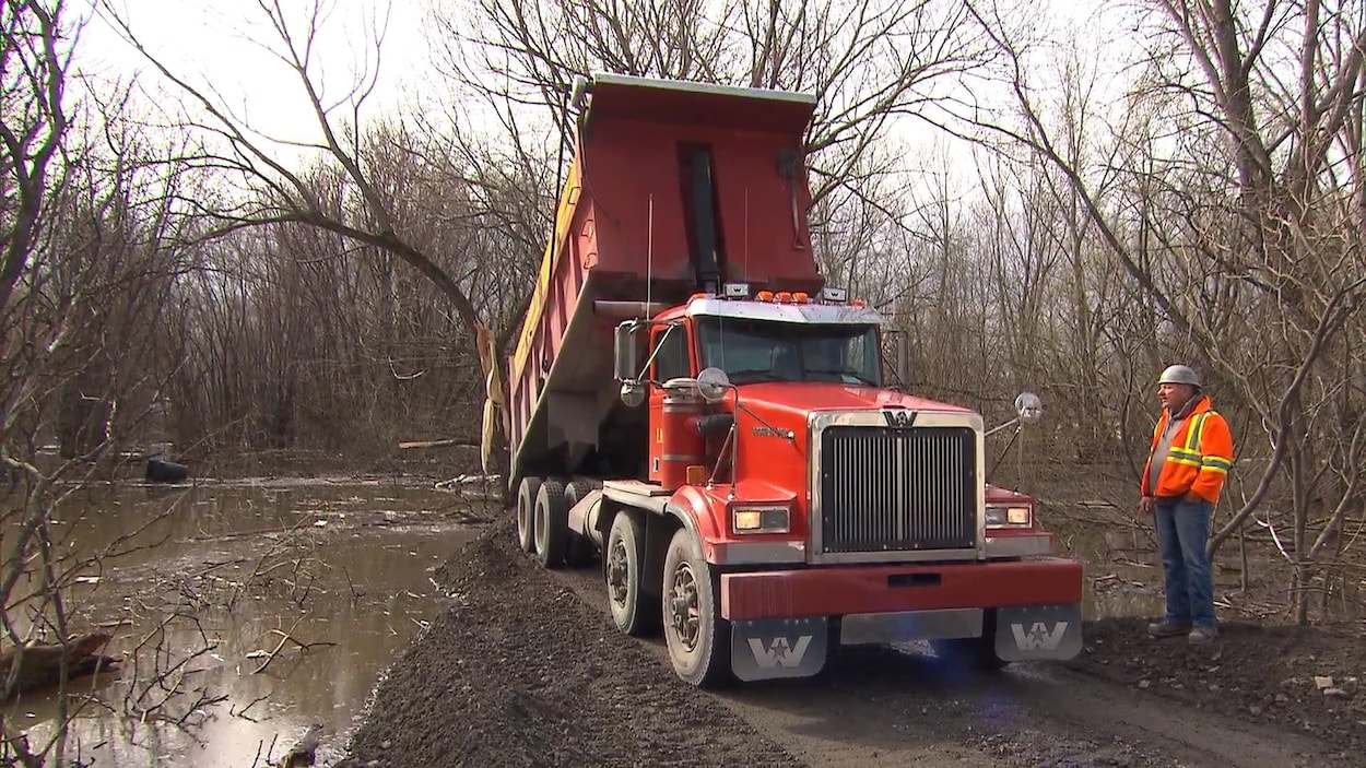 Un camion déverse du gravier dans l'eau.