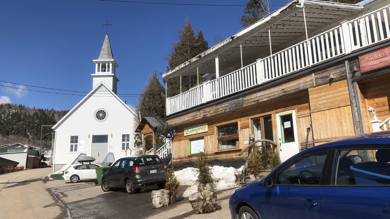 Quelques véhicules sont garés près de l'église de Sainte-Rose-du-Nord.