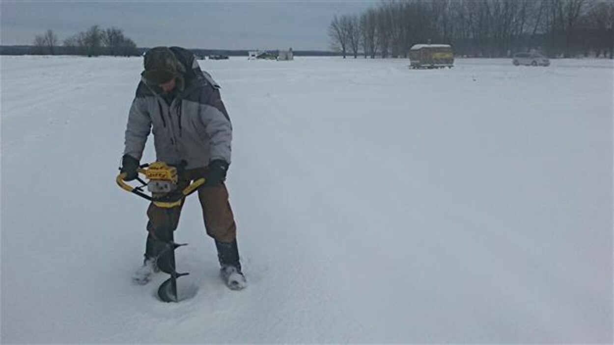 Un homme utilise une tarière à essence pour percer un trou dans la glace