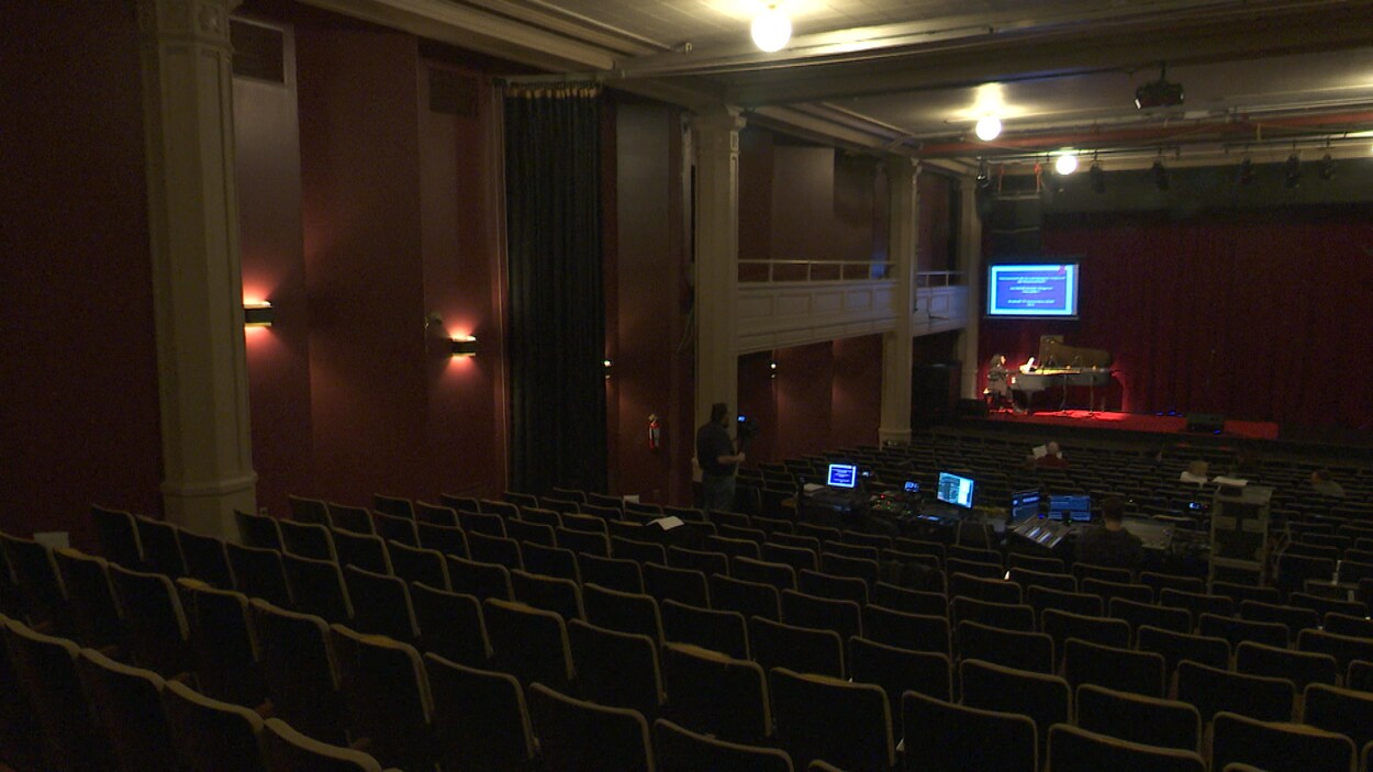 Intérieur de la salle André-Gagnon vide, alors qu'un pianiste pratique sur scène.