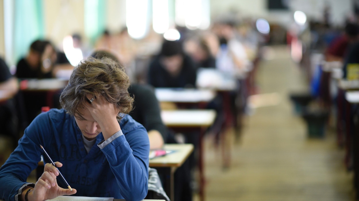 Un adolescent est penché sur son bureau dans une salle de classe.