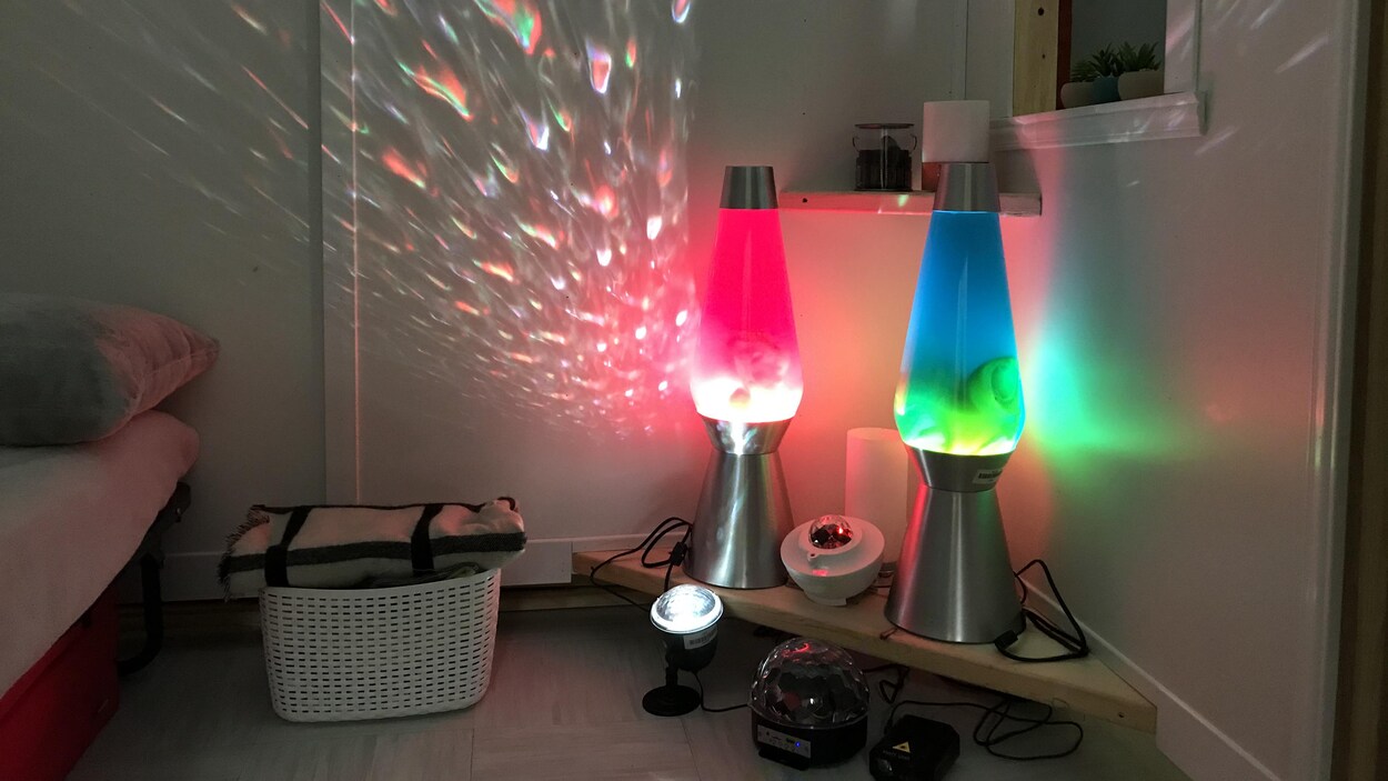 Une petite salle avec des lampes à lave et un lit.