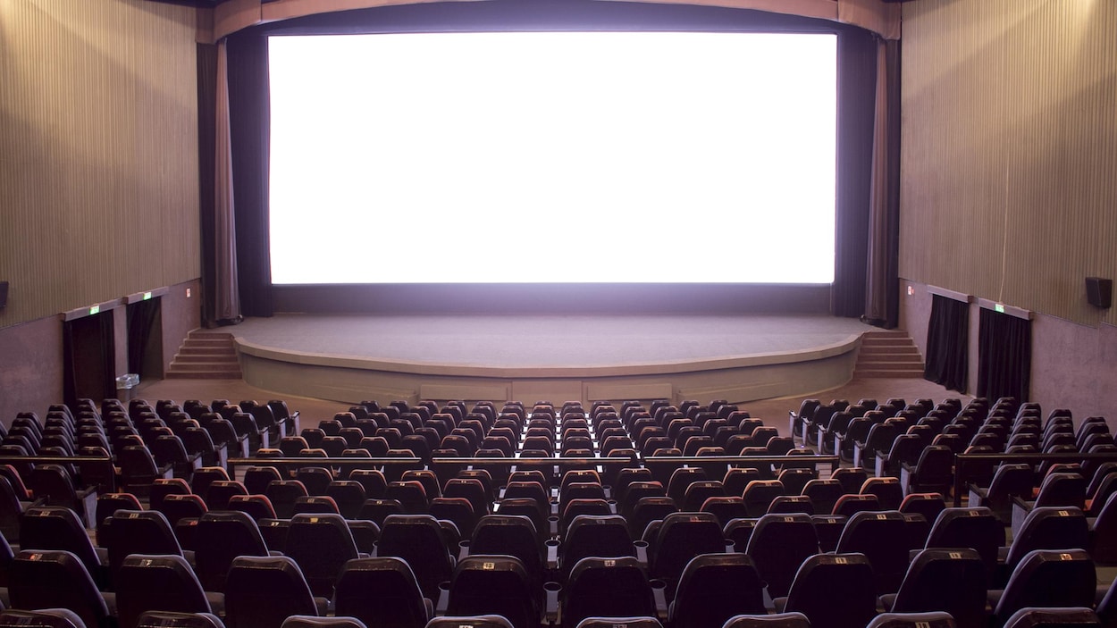Une salle de cinéma avec un écran blanc en arrière plan. Une salle de cinéma avec un écran blanc en arrière plan.