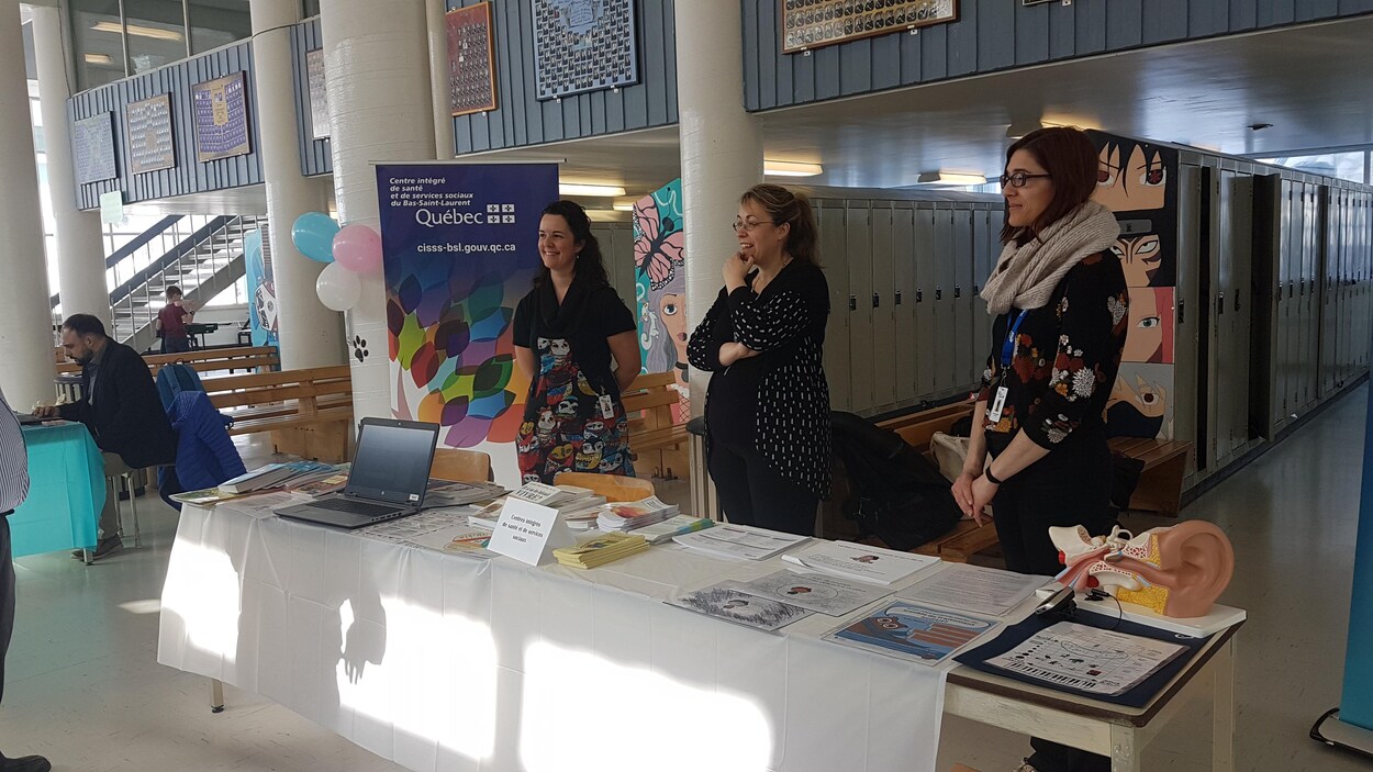 Trois dames se tiennent derrière une table au Salon des besoins particuliers.