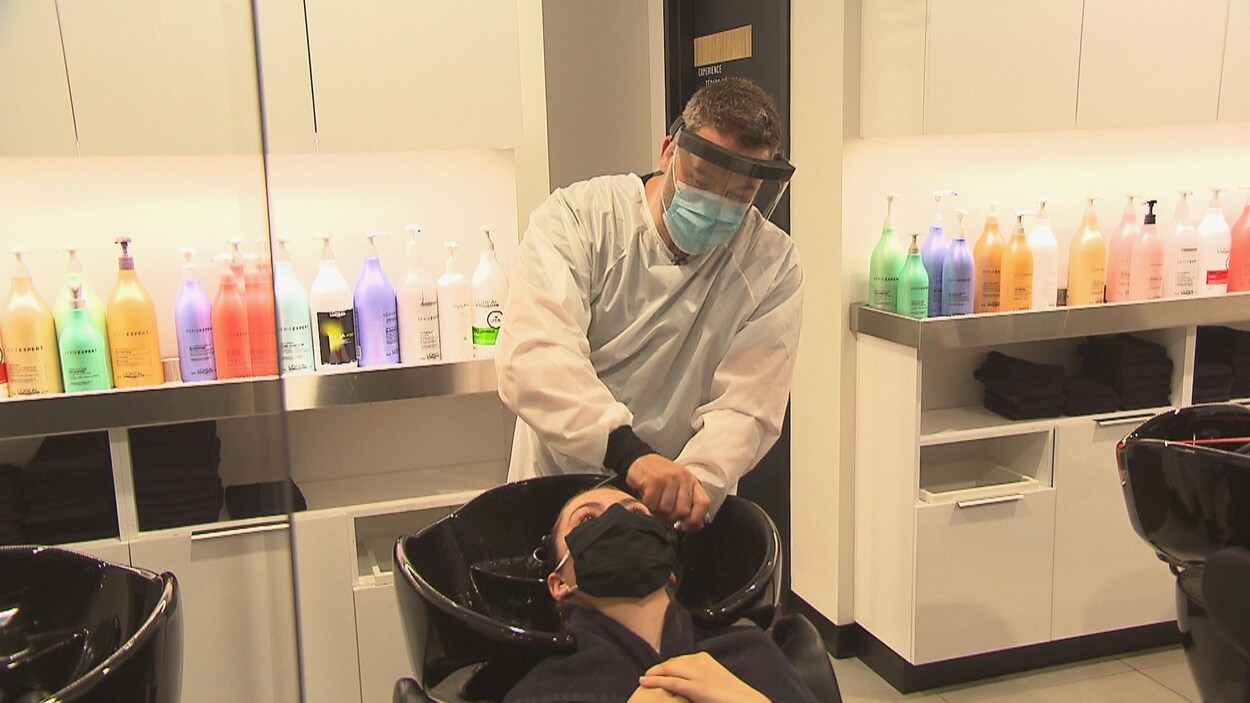 Un coiffeur lave les cheveux d'une cliente.
