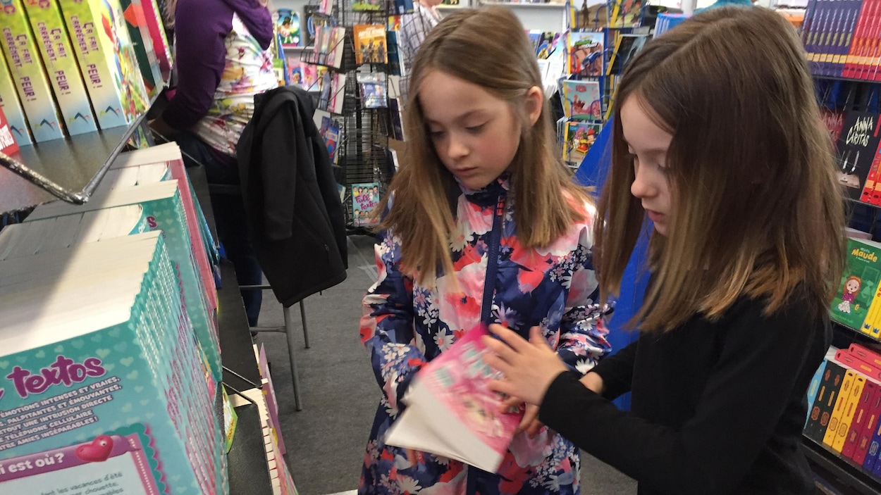Deux jeunes filles bouquinent à un salon du livre.