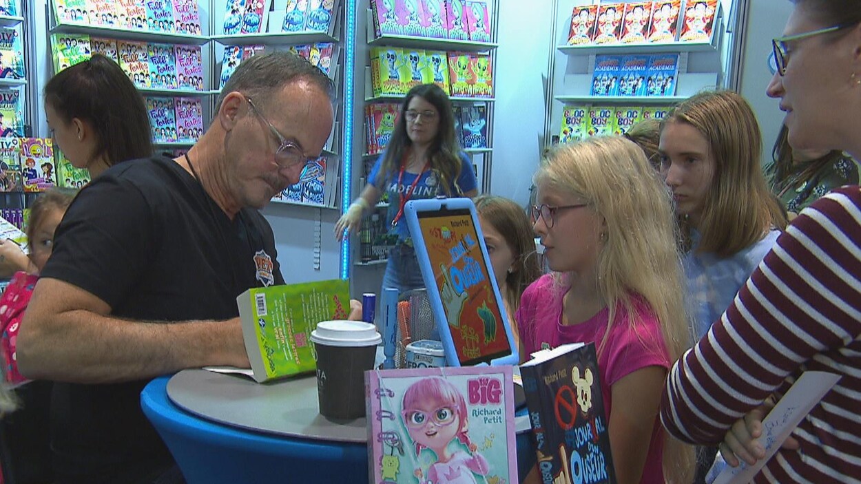 Un auteur signe un livre devant de jeunes lectrices.
