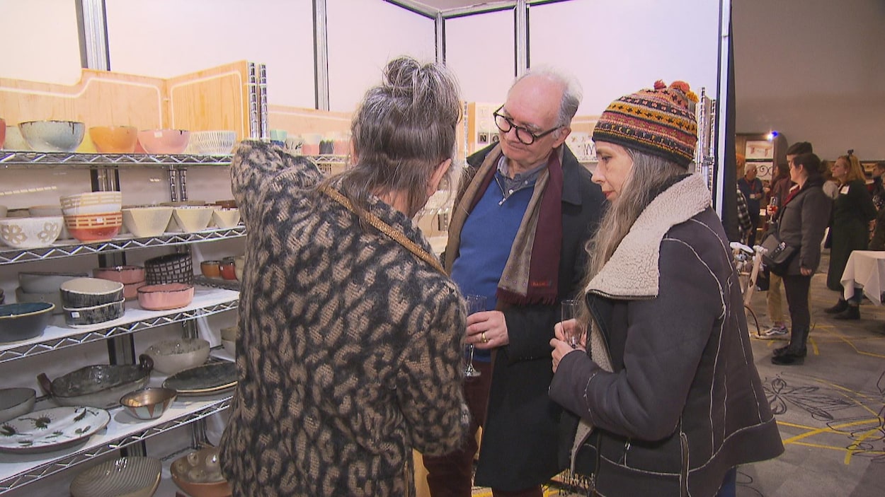 Une artisane et deux acheteurs potentiels sont engagés dans une conversation.