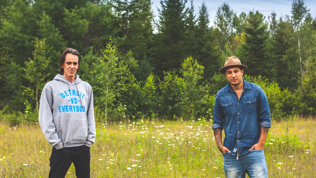 Les deux hommes sont debout dans une prairie.