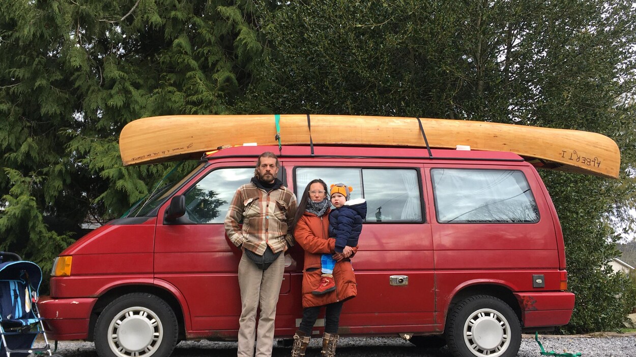 Un homme et une femme, l'air grave, devant une camionnette de marque Westfalia.