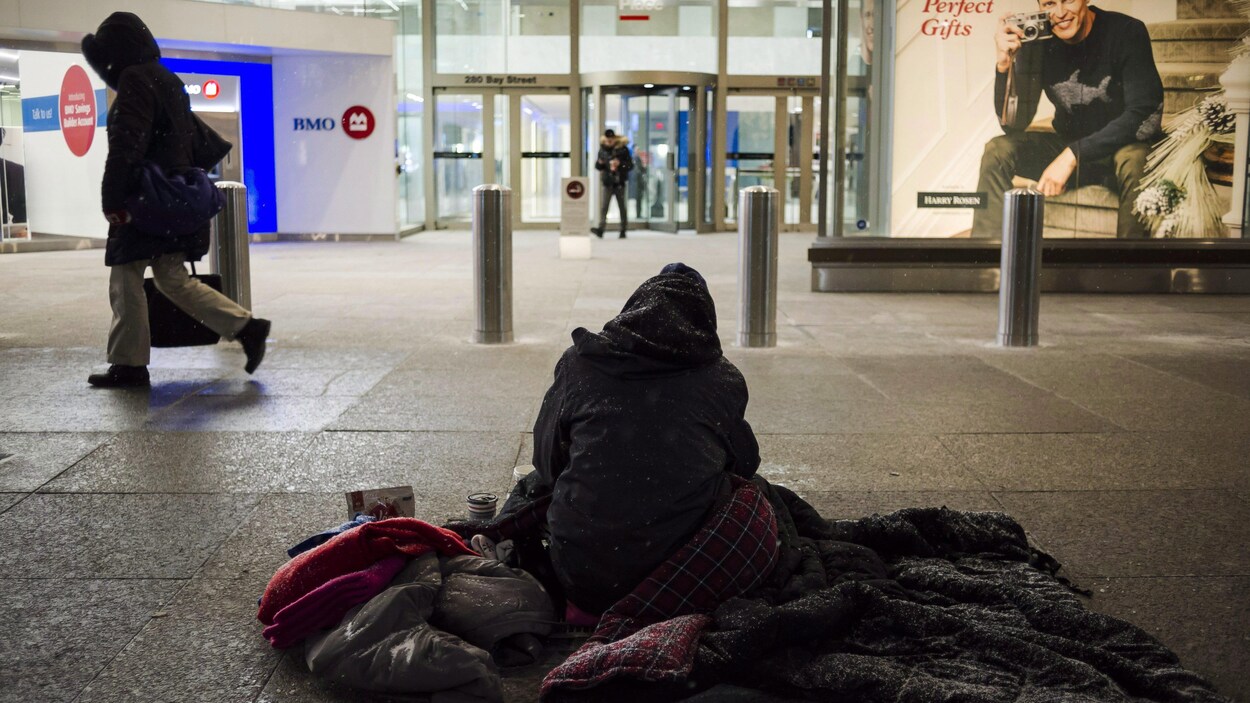 Un sans-abri sur le trottoir l'hiver à Toronto.