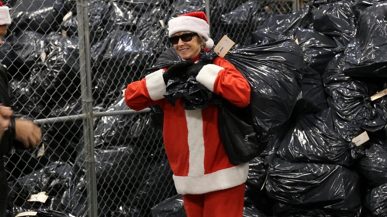 Une femme déguisée en mère Noël transporte un gros sac de vidanges. Une femme déguisée en mère Noël transporte un gros sac de vidanges.