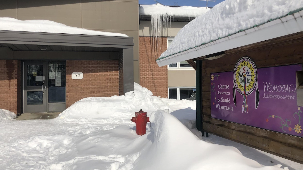 Panneau violet du centre des services de santé de Wemotaci avec le bâtiment