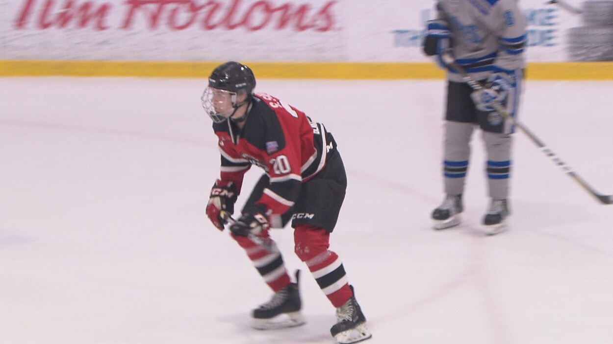 Samuel Savoie en action sur la patinoire durant un match. Un joueur adverse le suit de près.