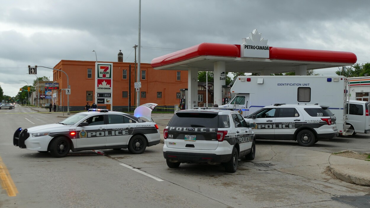 Des voitures de police entourent une station d'essence.