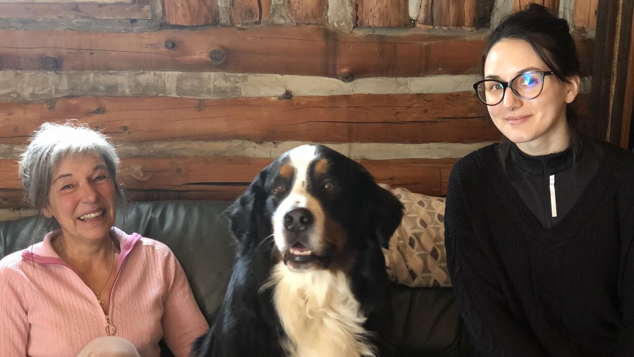 Deux femmes et un chien assis sur un canapé.