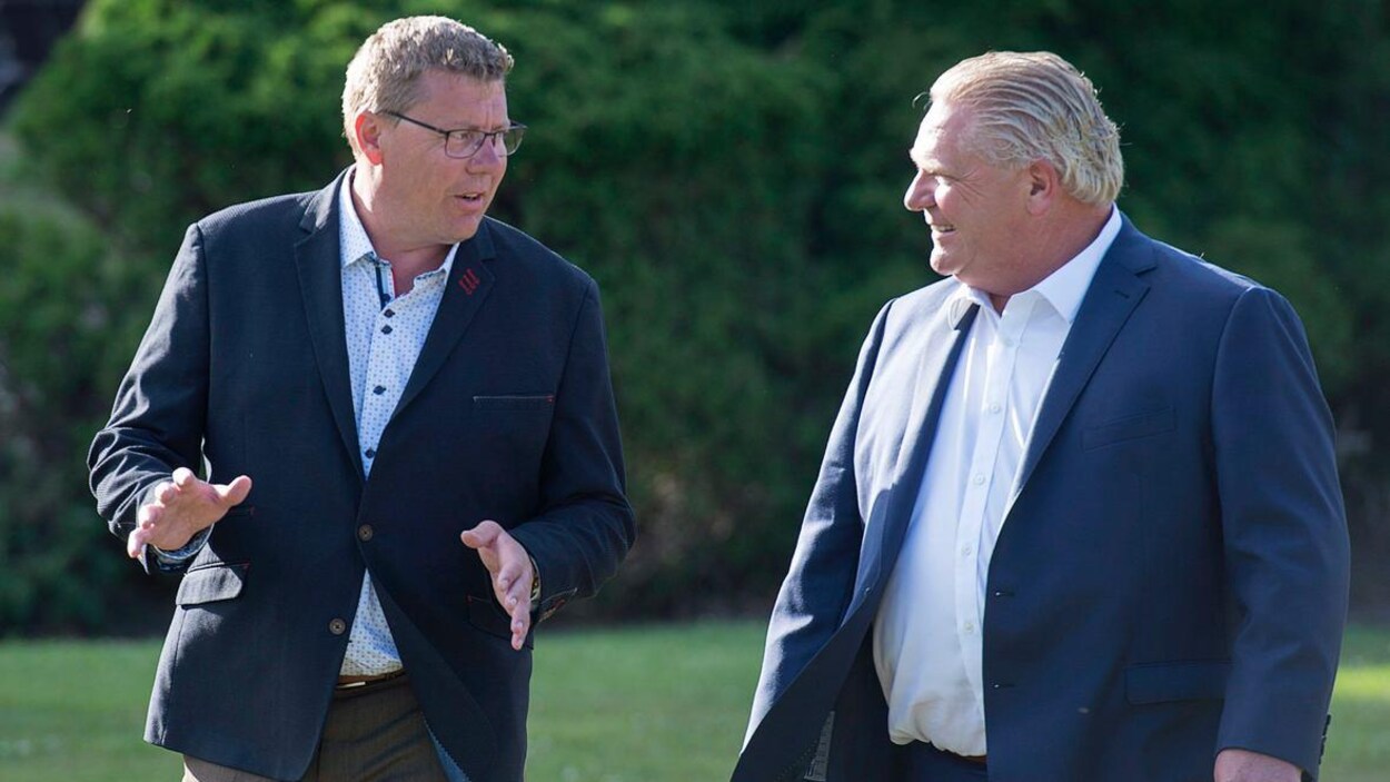 Scott Moe parle à Doug Ford dans un parc.