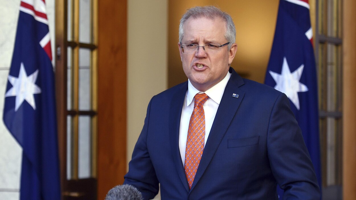 Scott Morrison parle debout devant un drapeau australien.