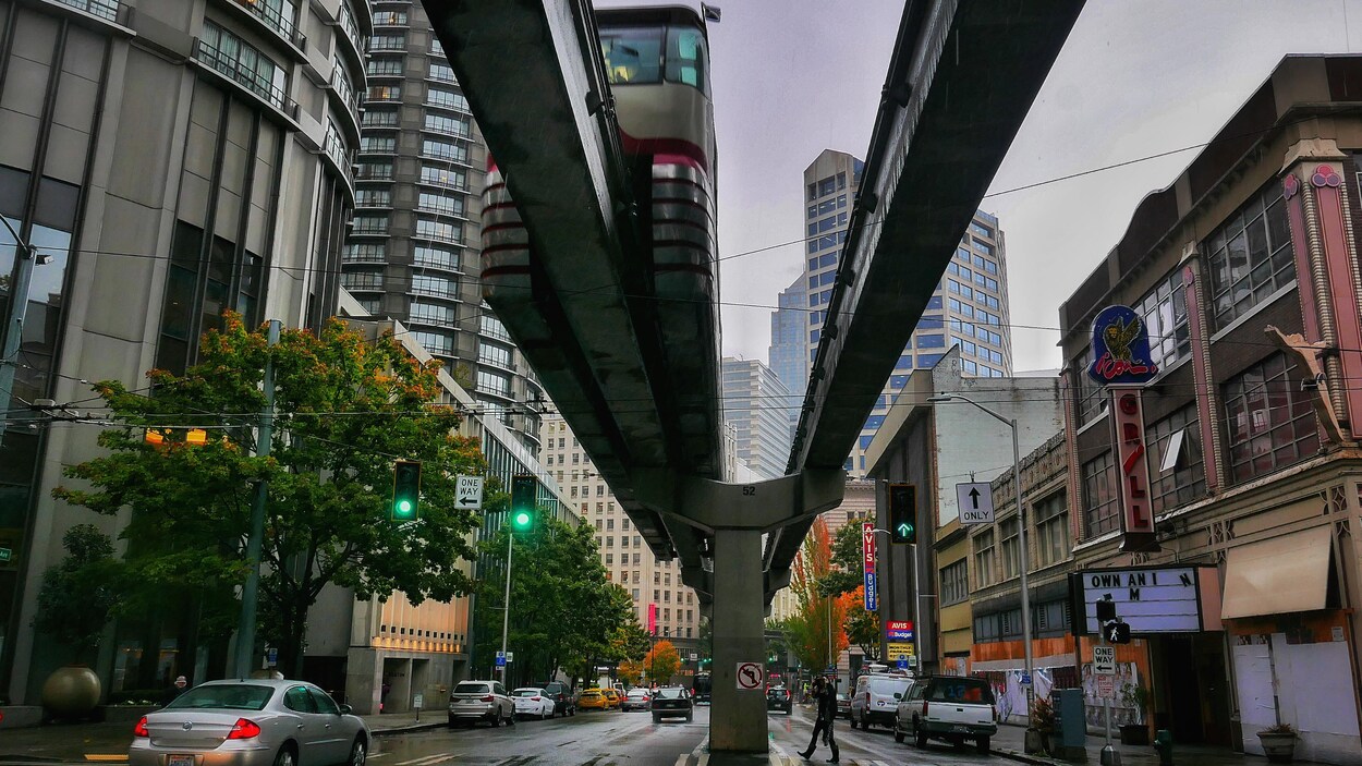 On voit des édifices du centre-ville de Seattle et, en contre-plongée, le monorail.