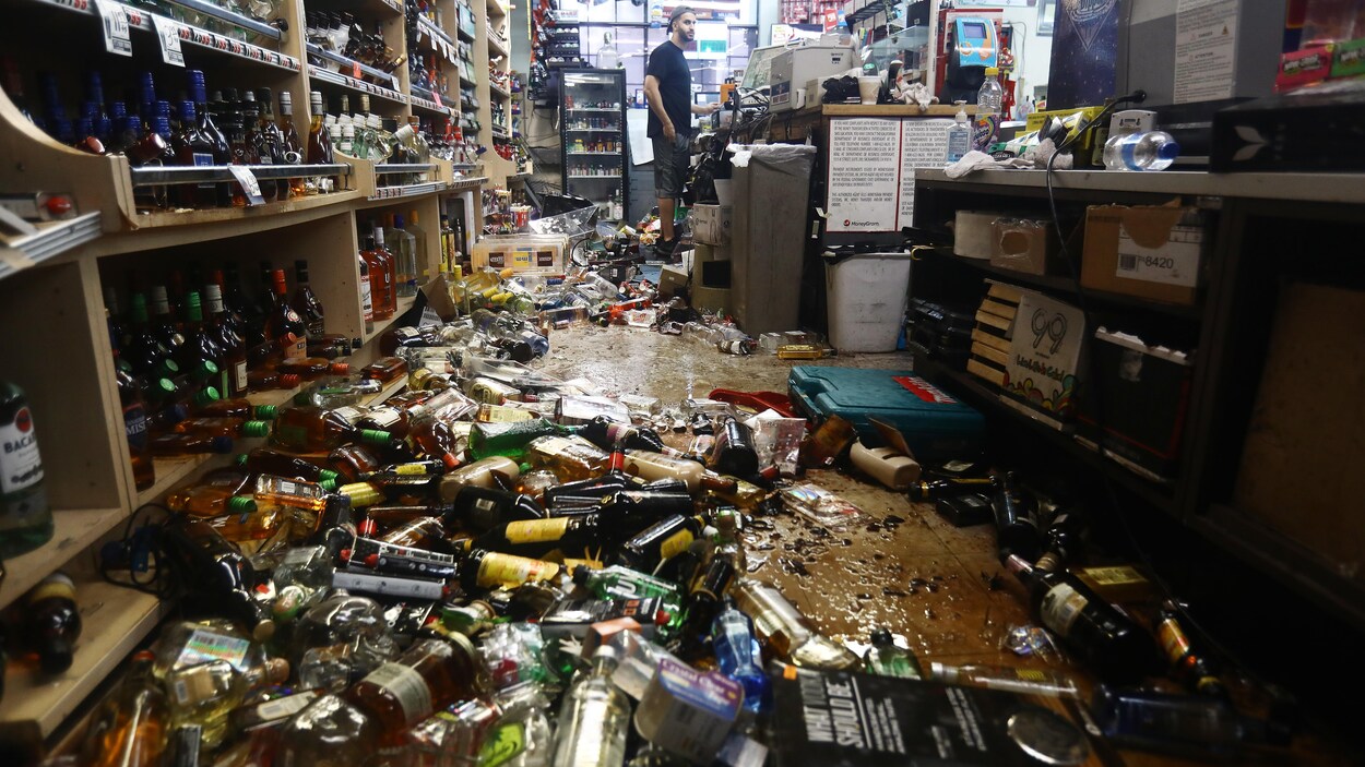 Des bouteilles d'alcool sont écrasées sur le sol d'un magasin.