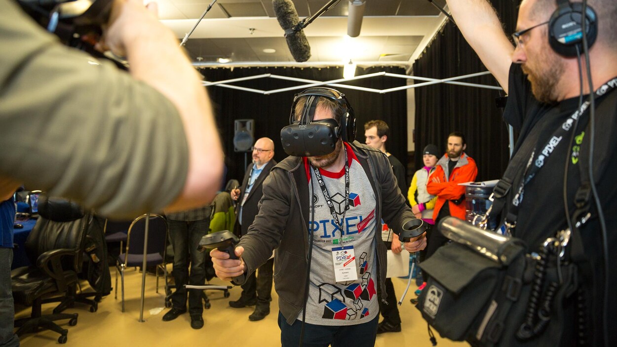 Un participant s'amuse avec un masque de réalité virtuelle pendant qu'un caméraman et un preneur de son l'enregistrent. Un participant s'amuse avec un masque de réalité virtuelle pendant qu'un caméraman et un preneur de son l'enregistrent.