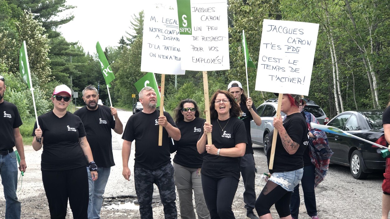 Des employés tiennent des pancartes à l'entrée du site touristique.