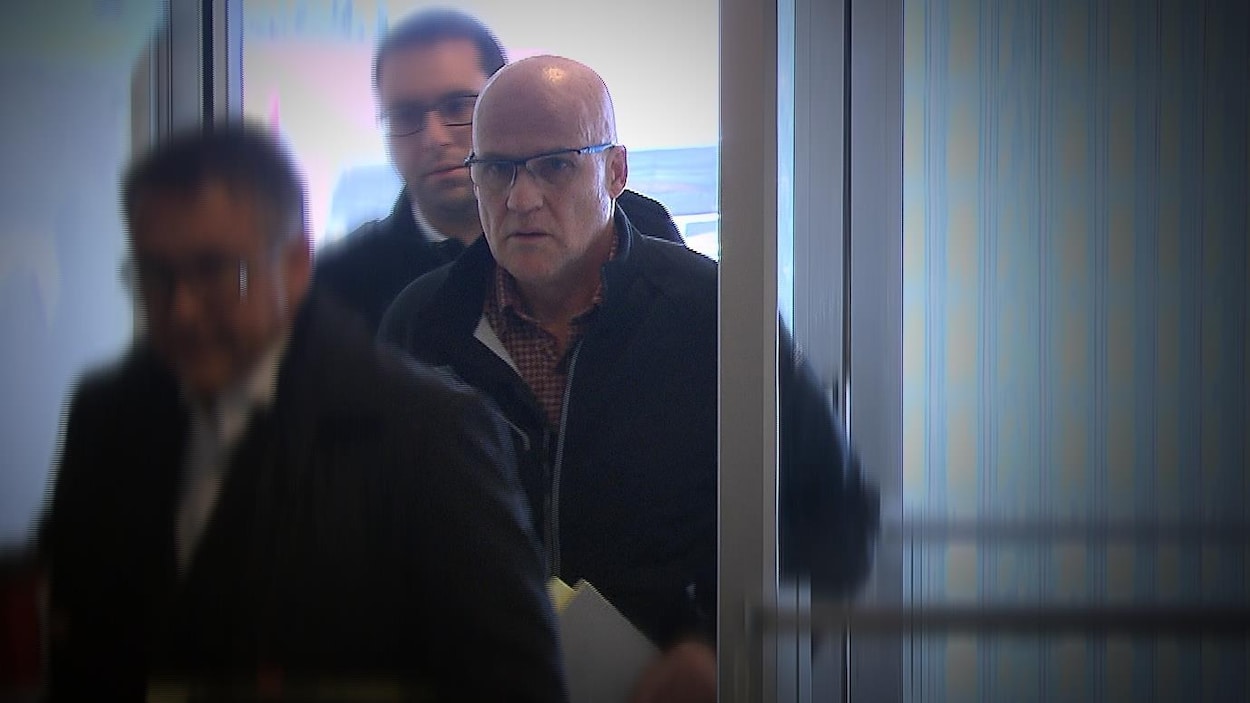 Précédé d'un homme et suivi d'un autre, Serge Carré entre à la cour itinérante de Forestville pour sa comparution.