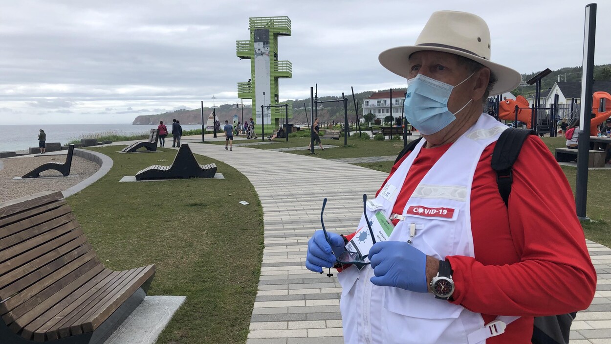 Serge Soucy porte un masque, des gants ainsi qu'une veste qui indique qu'il fait partie de l'escouade COVID-19.