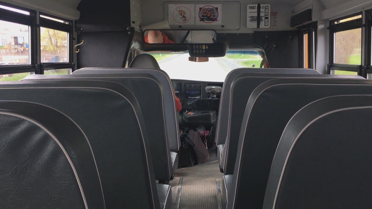 L'intérieur d'un autobus avec des bancs et un chauffeur.
