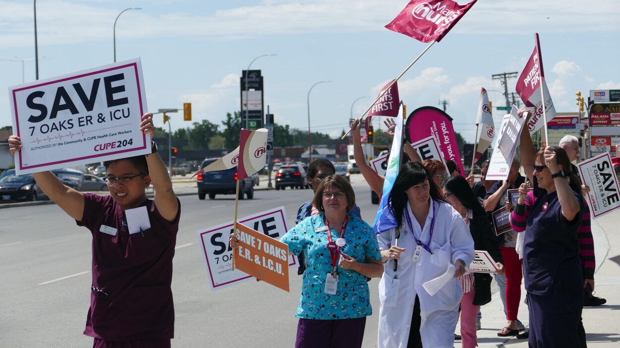 Des infirmiers et d'autres professionnels de la santé marchent dans la rue avec diverses pancartes.