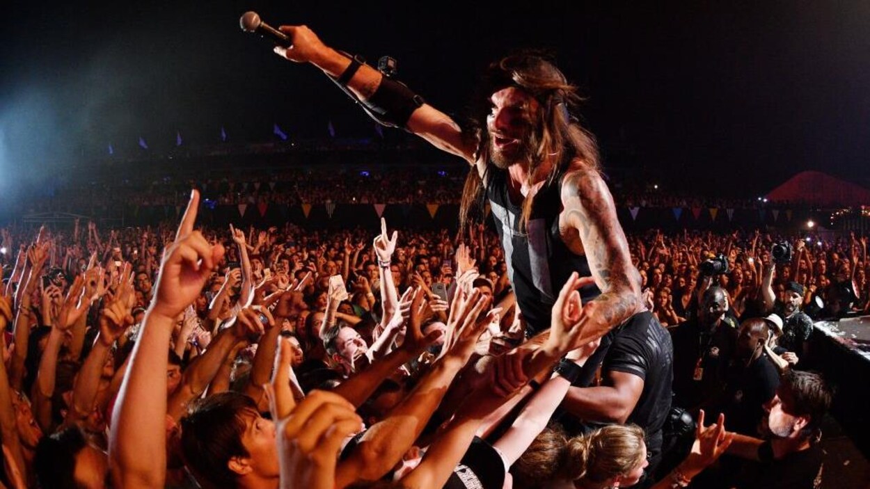 Un chanteur tient un micro au milieu de la foule.