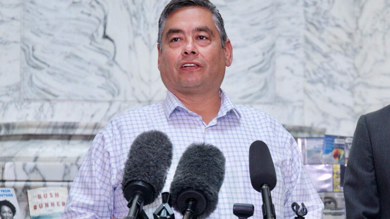 Un homme parle devant plusieurs microphones.