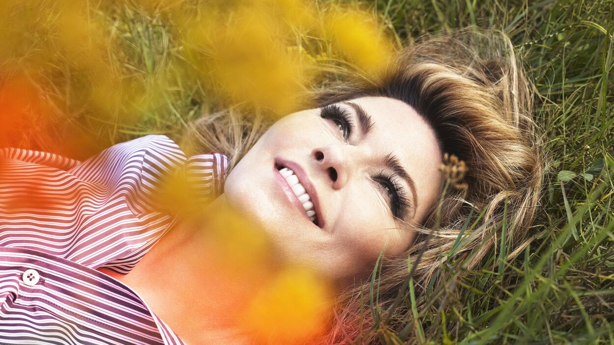La chanteuse allongée dans un champ d'herbe et de fleurs