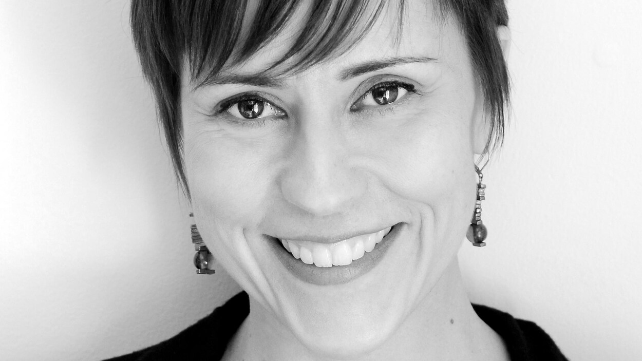 Portrait en noir et blanc dune femme aux cheveux courts qui sourit à la caméra.