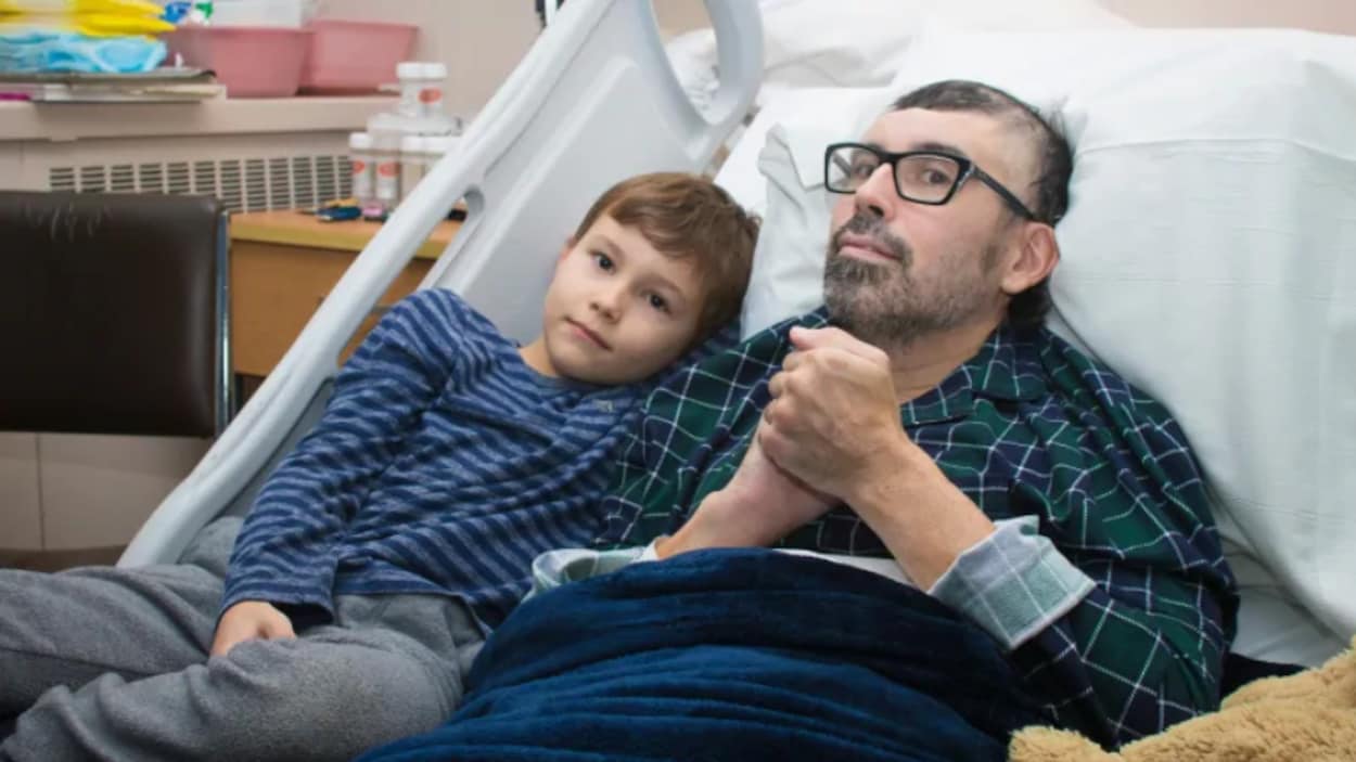 Un homme avec son fils sur un lit d'hôpital.