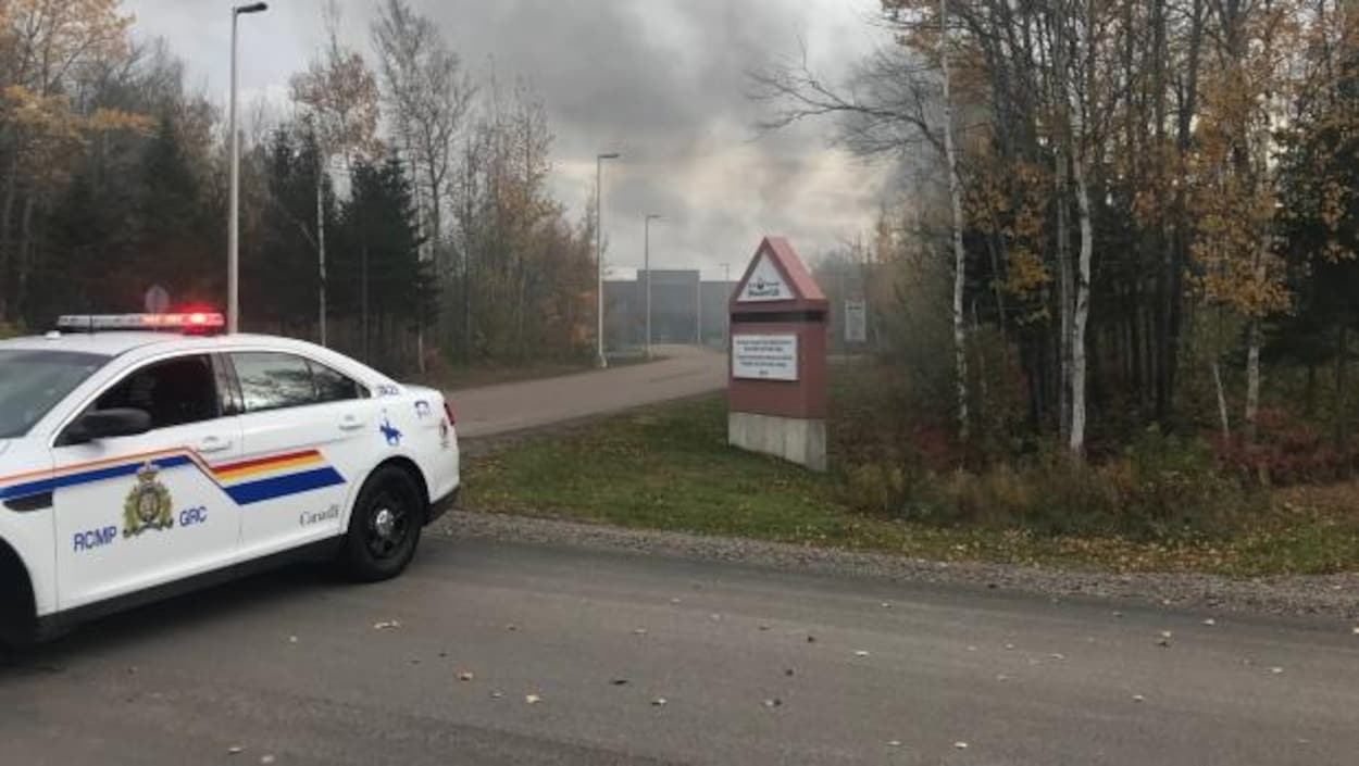 Une voiture de police devant la prison de laquelle s'échappe un énorme panache de fumée