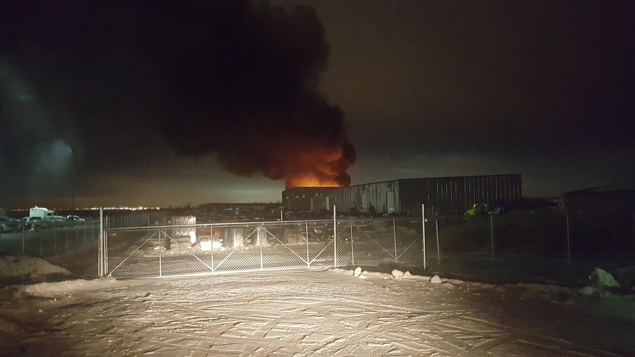 Un bâtiment en feu d'où s'échappe une épaisse fumée noire.