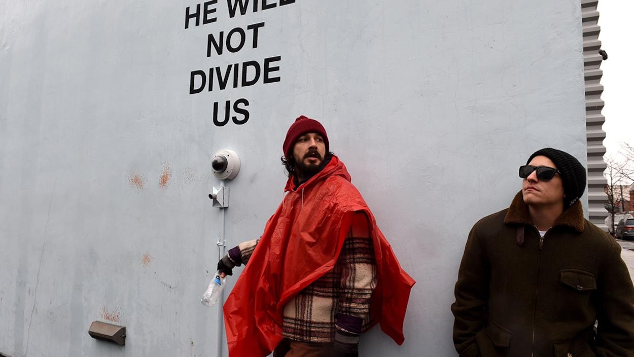 Shia LaBeouf devant l'installation « He Will Not Divide Us » au Museum of the Moving Image à Queens, New York Shia LaBeouf devant l'installation « He Will Not Divide Us » au Museum of the Moving Image à Queens, New York