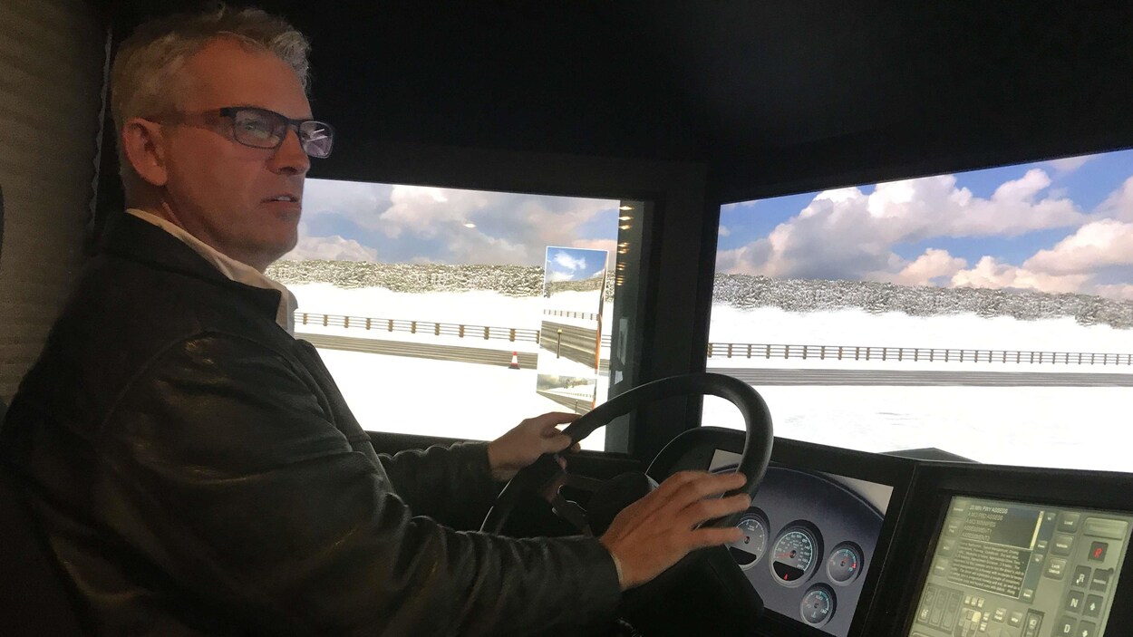 Un homme assis au volent d'un simulateur d'autobus scolaire teste sa conduite hivernale Un homme assis au volent d'un simulateur d'autobus scolaire teste sa conduite hivernale