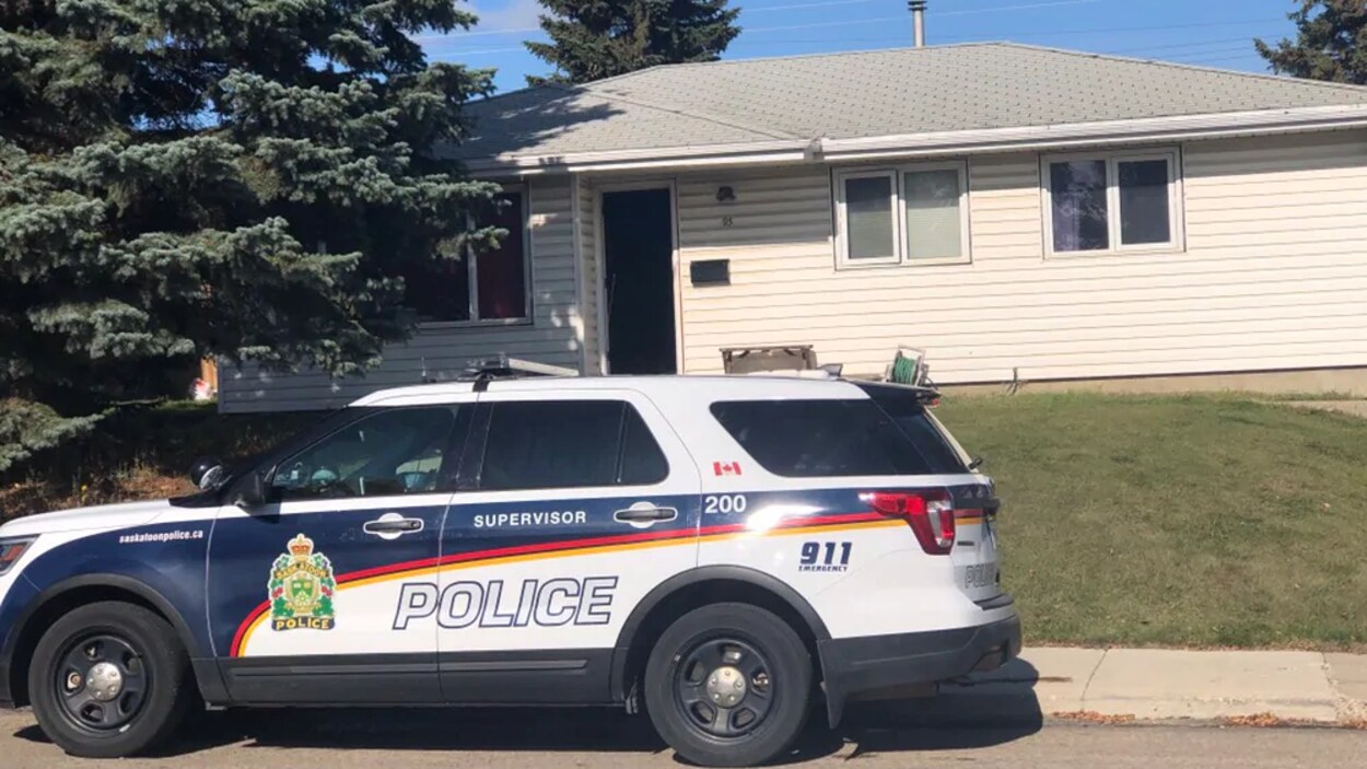 Une voiture de police de type véhicule utilitaire sport devant une maison à 1 étage.