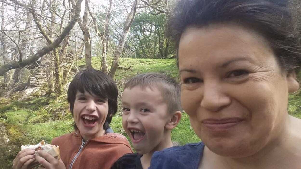 Une femme photographiée de près en compagnie de deux enfants.