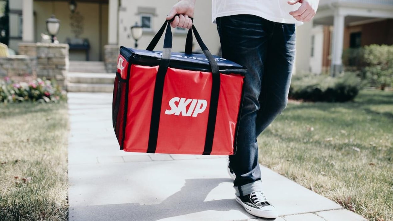 Un homme marche avec un sac de livraison rouge.