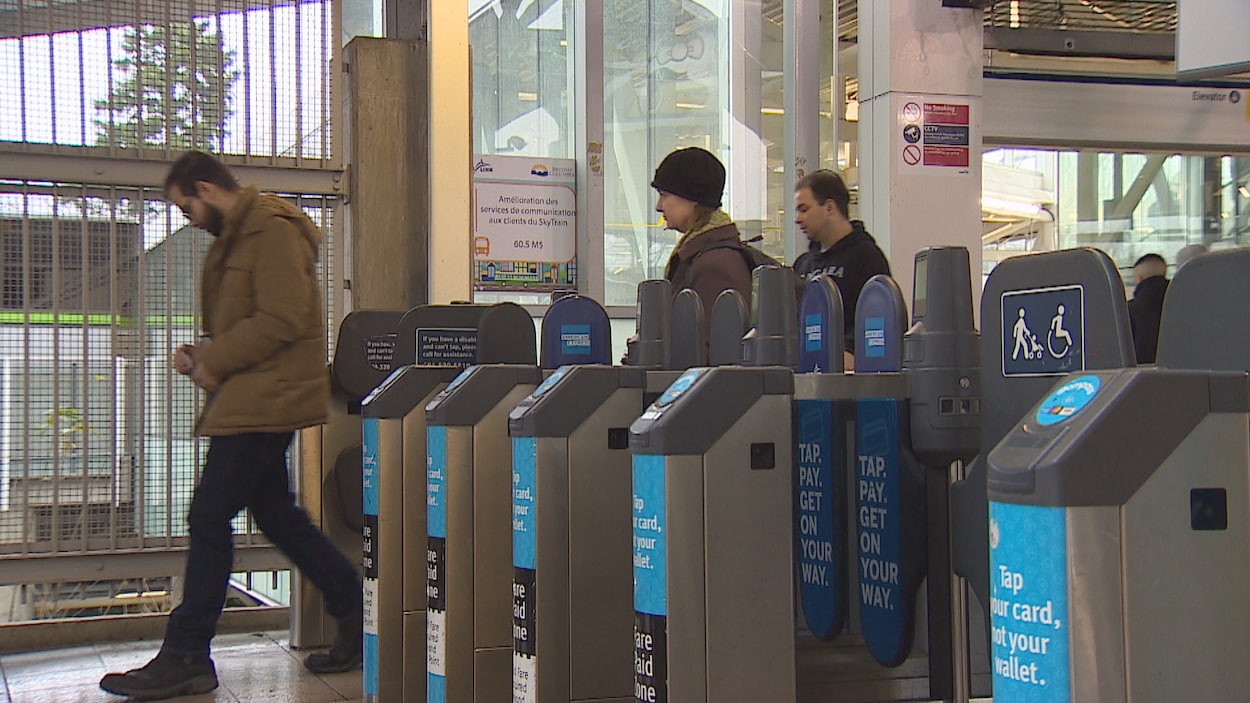 Des usagers du SkyTrain quittent une station de métro en passant par les portillons.