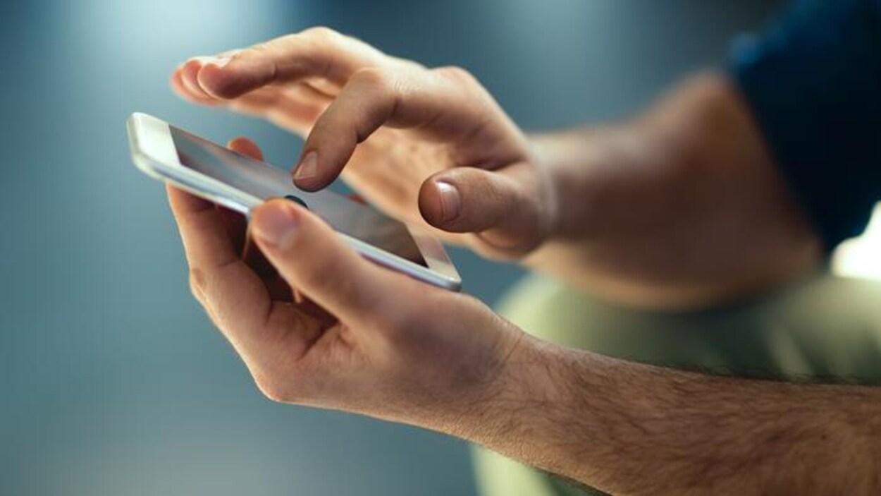 Un téléphone cellulaire entre les mains d'un homme.