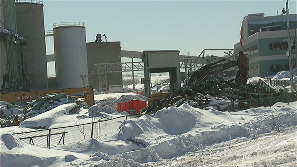 Un grue démolit des structures industrielles, dans la neige. Un grue démolit des structures industrielles, dans la neige.