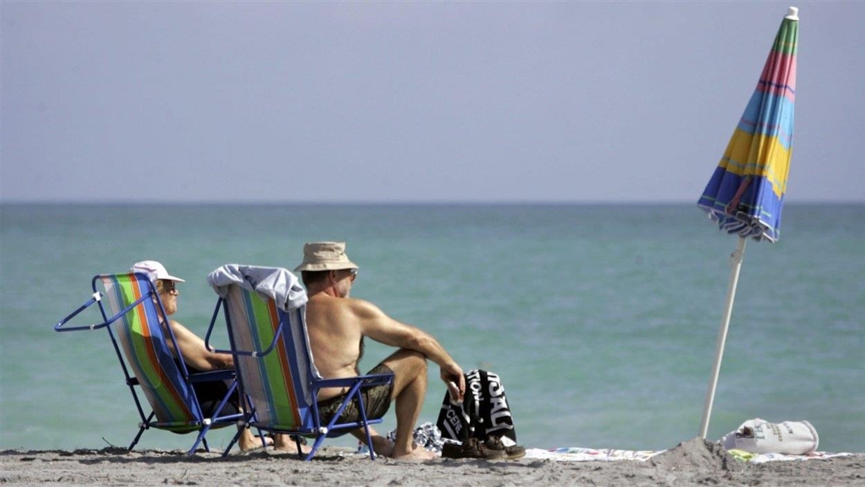 Un homme et une femme sont assis sur des chaises à la plage.