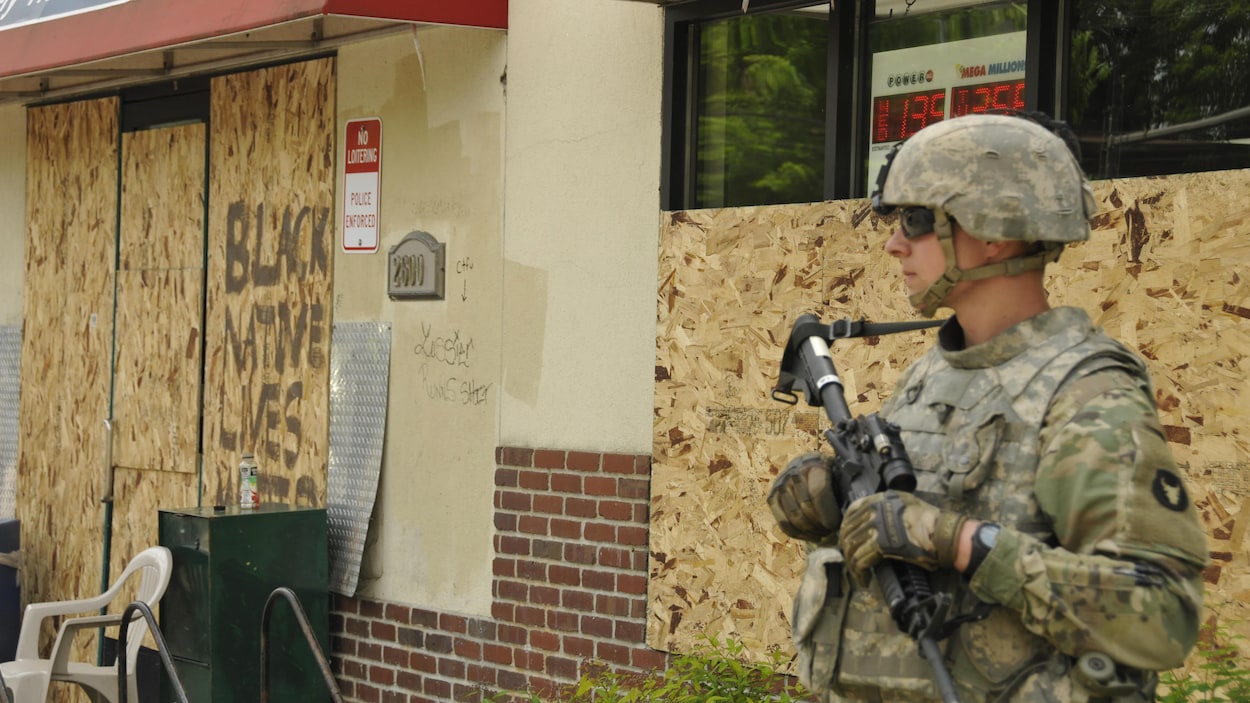 Un soldat de la garde nationale, mitraillette à la main, monte la garde devant un restaurant.