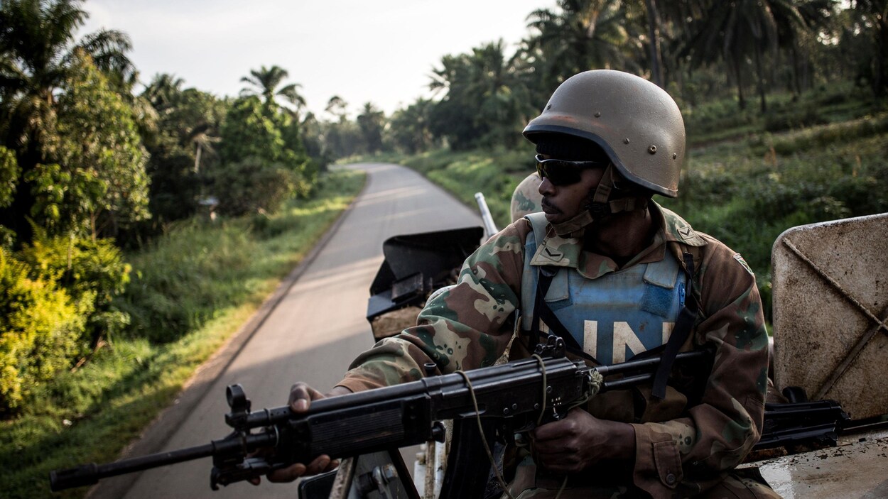 Un soldat de l'ONU assis sur un véhicule arme à la main.
