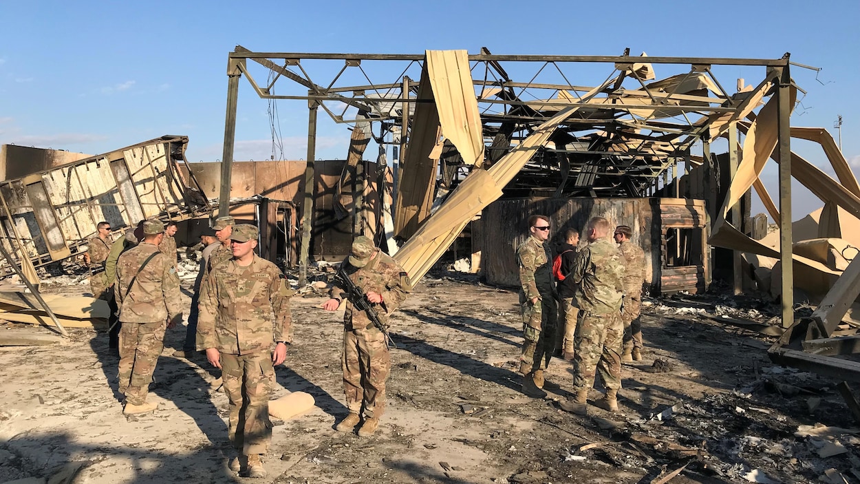 Plusieurs soldats discutent près de la carcasse d'une structure.